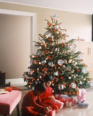 Niños jugando junto a árbol navideño adornado.