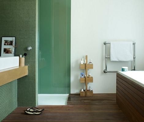 Baño moderno con azulejos verdes y suelo de madera.